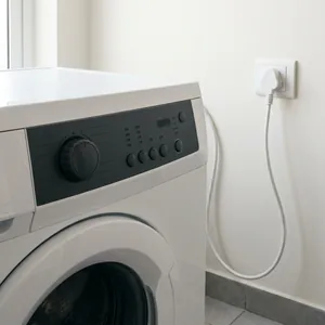 Unlit washing machine control panel with the plug hanging loose from the socket.